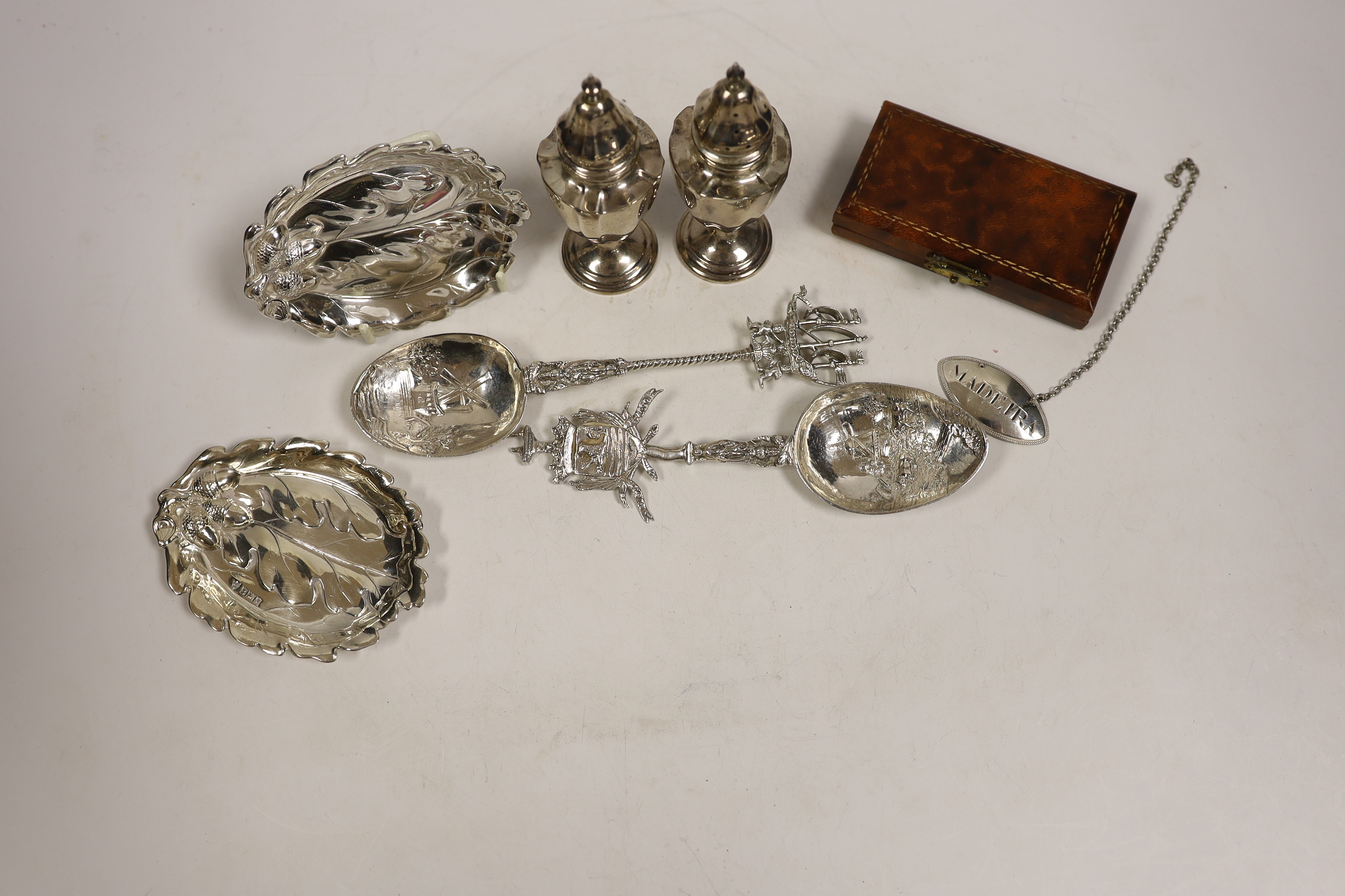 Small silver including a pair of Edwardian silver pepperettes, London, 1906, two continental import marked silver spoons, a silver dish, Georgian wine label and a cased set of four silver and enamel bridge pencils, impor